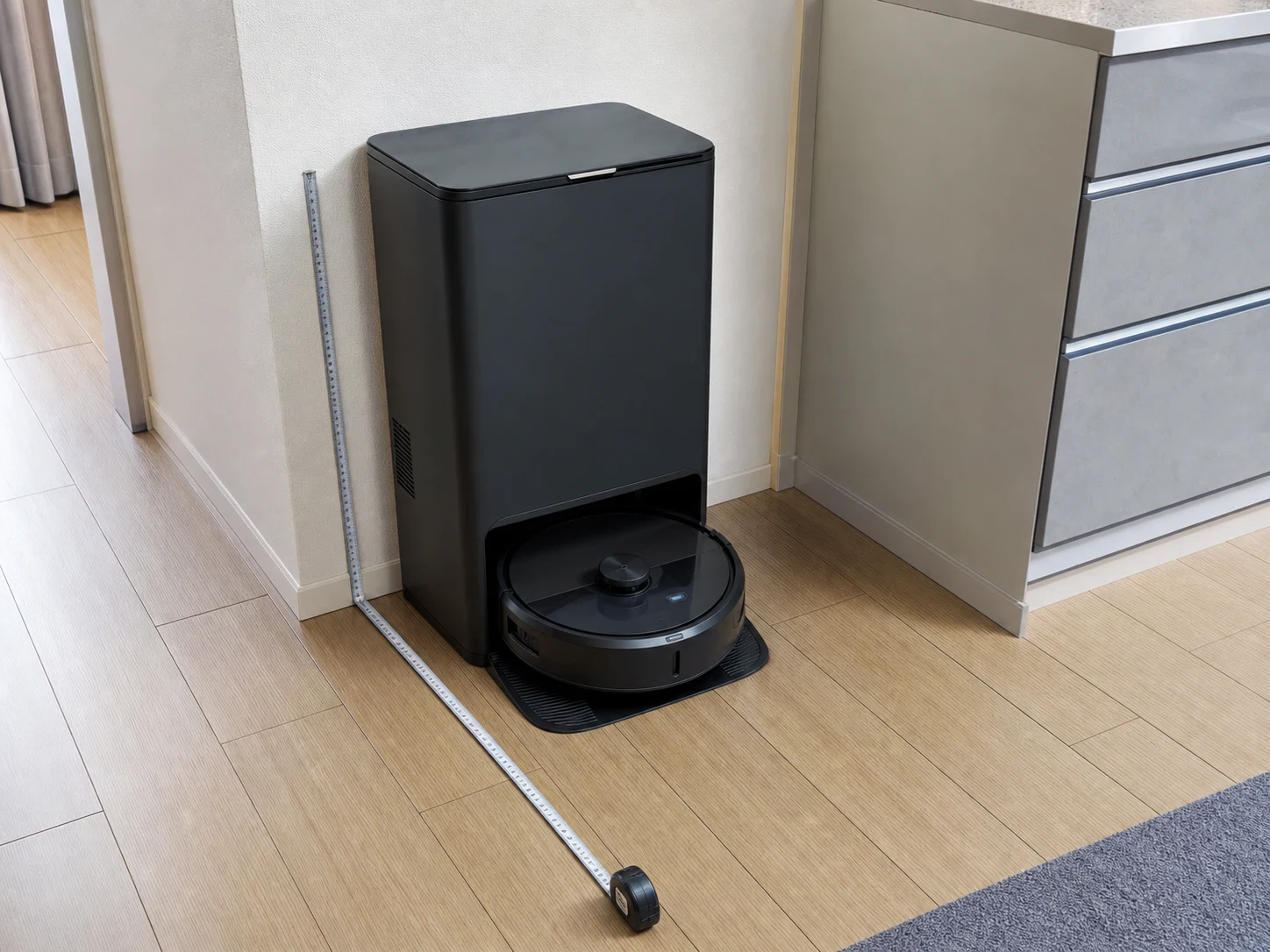 壁際のドックからフローリングへ出るロボット掃除機