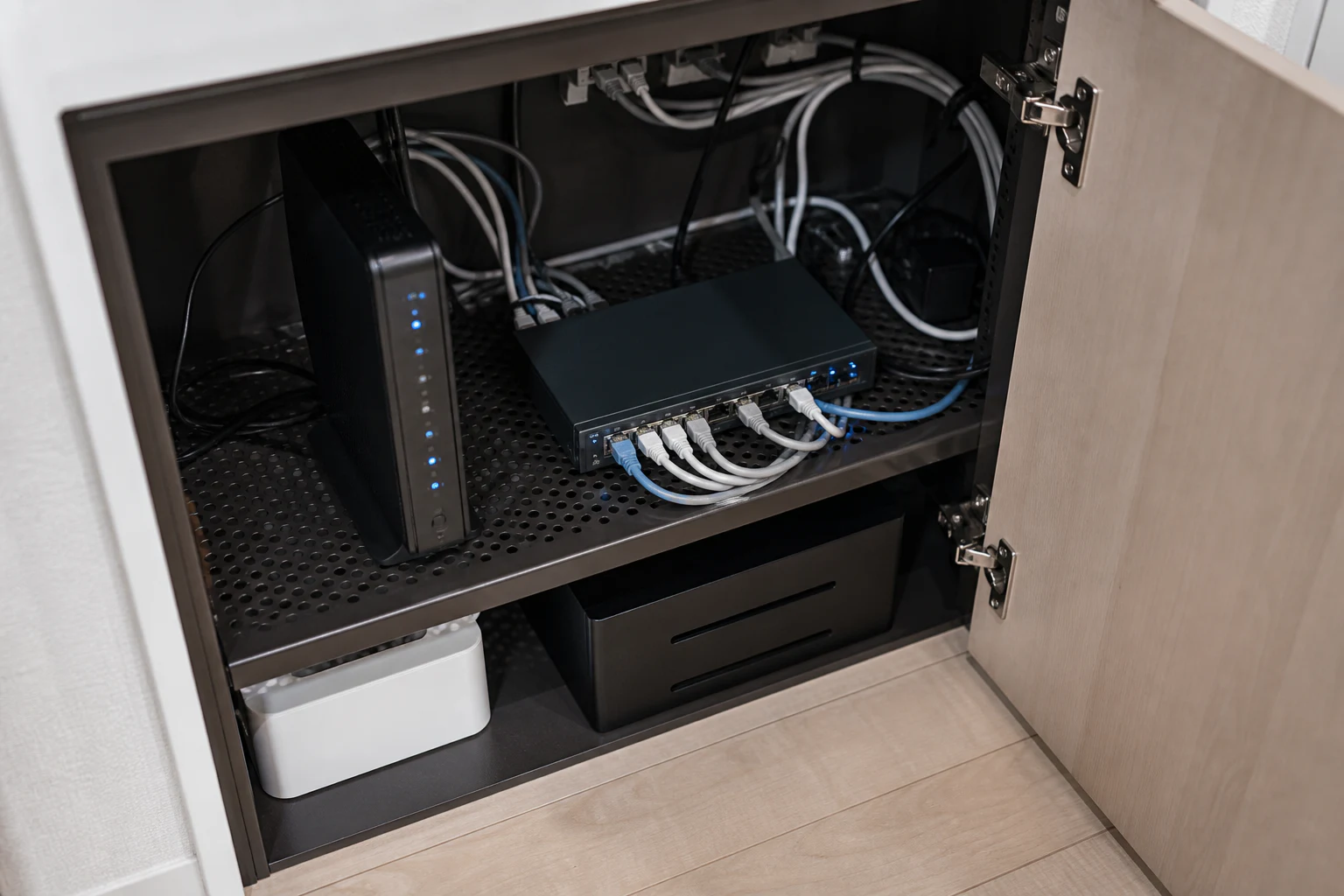 家庭用ルーターとスイッチ、LANケーブルを整理した通信機器棚のイメージ