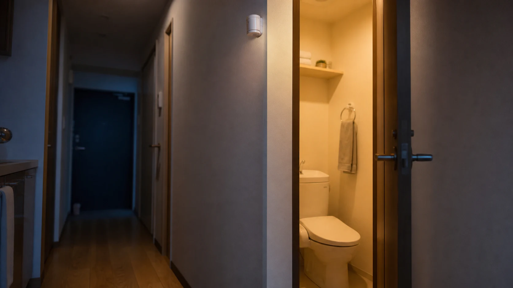 夜の日本の廊下でトイレの照明が自動点灯し、入口の人感センサーが動線を検知するイメージ